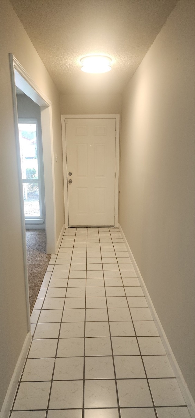 hall featuring a textured ceiling and light tile patterned floors