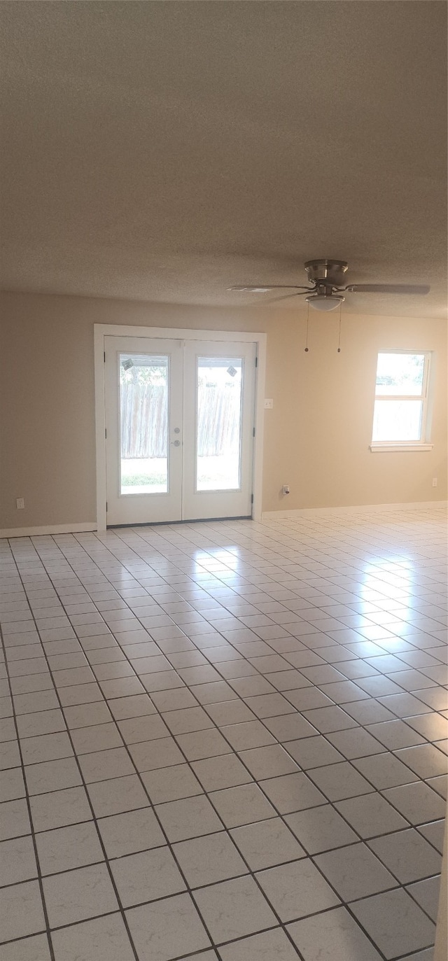 tiled empty room with ceiling fan and french doors