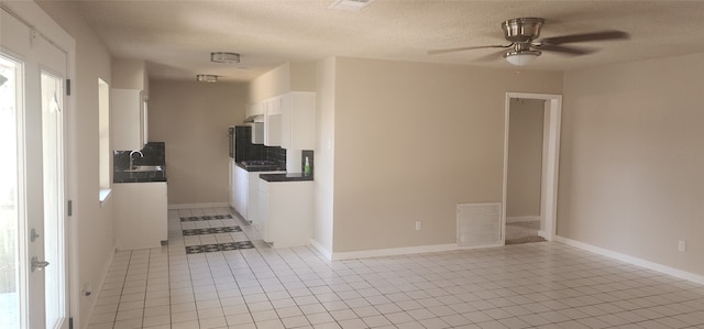 corridor with a textured ceiling, light tile patterned floors, and sink