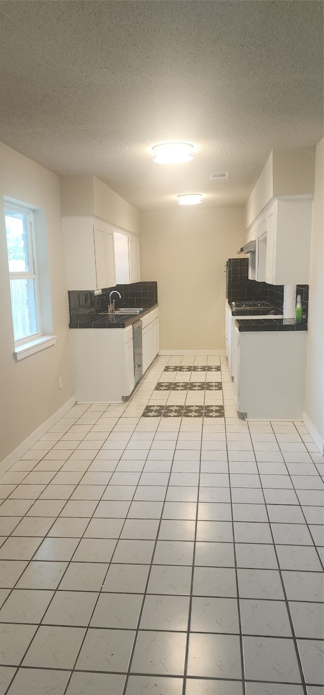 kitchen featuring white cabinets, light tile patterned floors, tasteful backsplash, and a textured ceiling