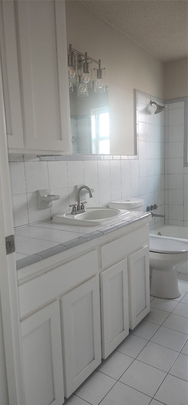 full bathroom featuring a textured ceiling, tasteful backsplash, tiled shower / bath combo, vanity, and toilet