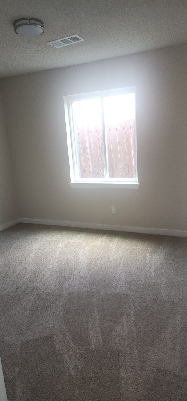 carpeted empty room with a textured ceiling