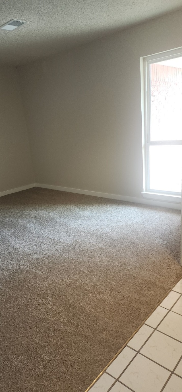 tiled empty room featuring a textured ceiling