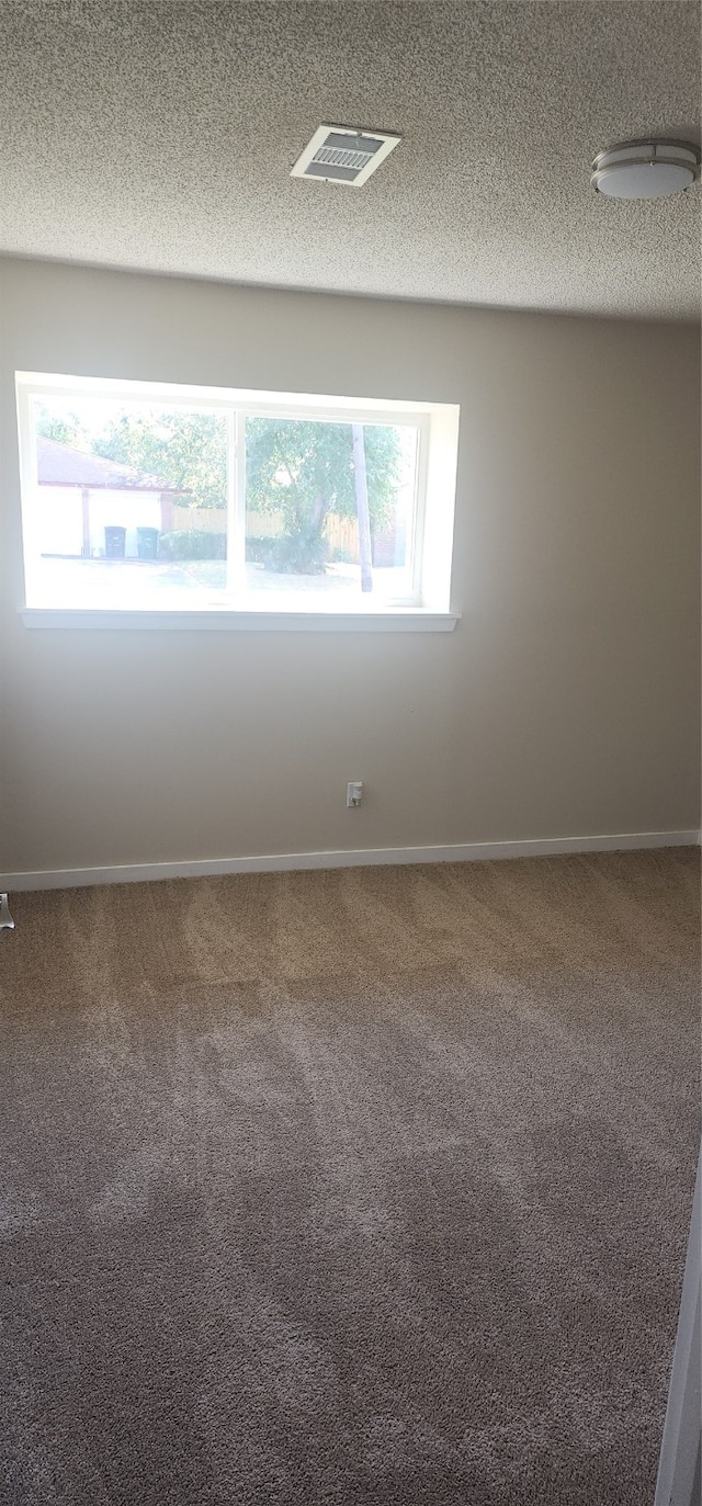 carpeted spare room featuring a textured ceiling