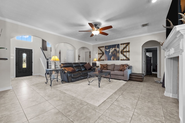 living room featuring light tile patterned floors, baseboards, visible vents, arched walkways, and crown molding