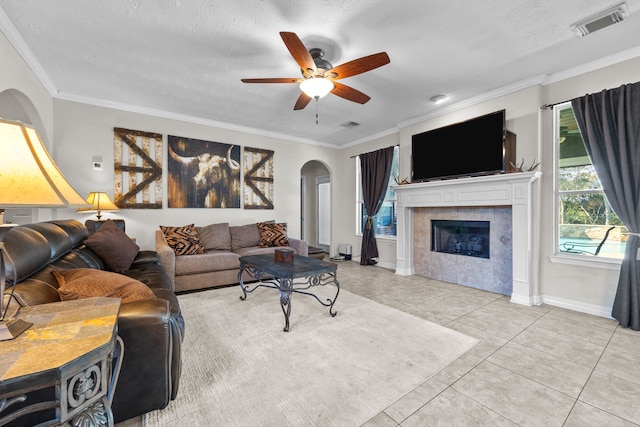 living area featuring arched walkways, light tile patterned floors, visible vents, and crown molding