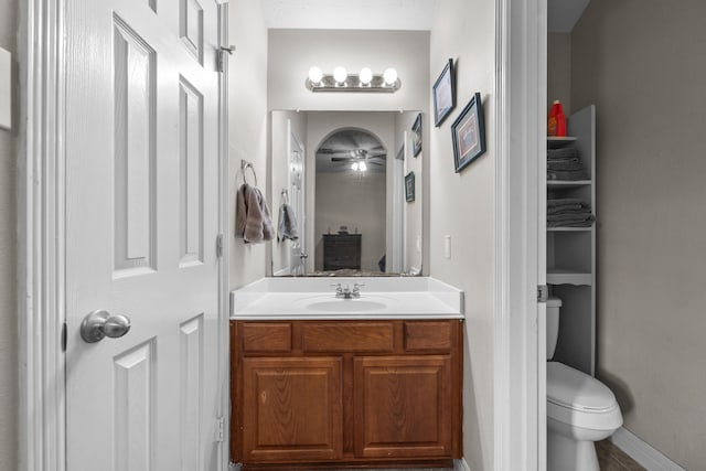 bathroom featuring ceiling fan, vanity, toilet, and baseboards