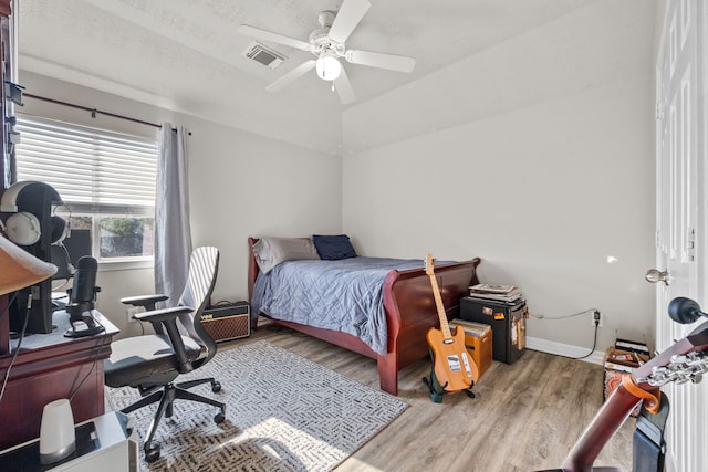 bedroom with a ceiling fan, baseboards, visible vents, and wood finished floors