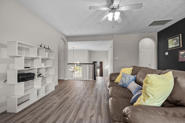 living room with visible vents, arched walkways, wood finished floors, a textured ceiling, and ceiling fan with notable chandelier