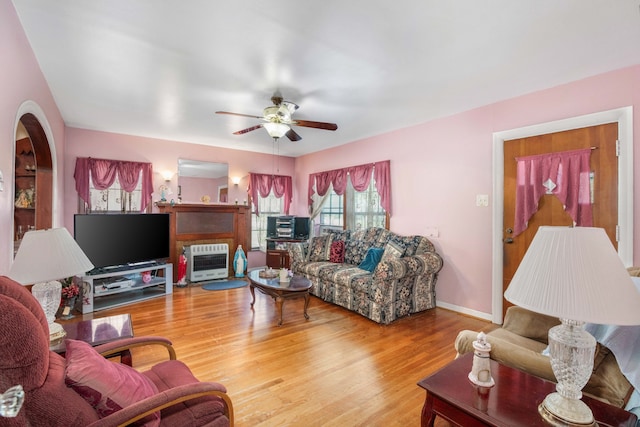 living room featuring wood-type flooring, ceiling fan, and heating unit