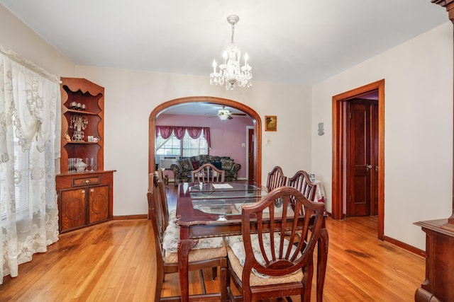 dining room with ceiling fan with notable chandelier and light hardwood / wood-style floors