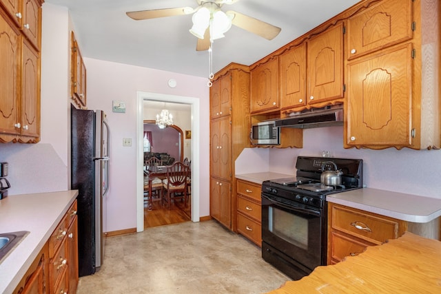 kitchen with appliances with stainless steel finishes and ceiling fan with notable chandelier