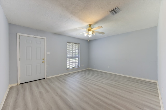 empty room with a textured ceiling, light hardwood / wood-style floors, and ceiling fan