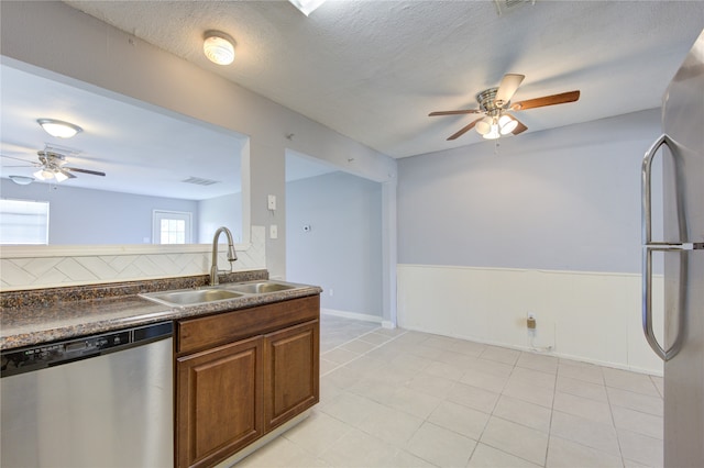 kitchen featuring appliances with stainless steel finishes, decorative backsplash, light tile patterned floors, a textured ceiling, and sink