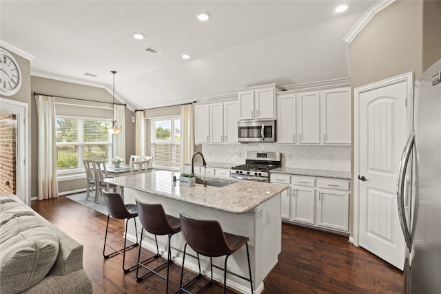 kitchen featuring appliances with stainless steel finishes, vaulted ceiling, dark wood-type flooring, white cabinets, and pendant lighting