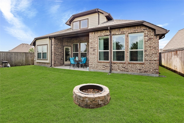 rear view of property featuring a lawn, a patio, and an outdoor fire pit