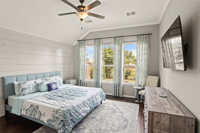 bedroom with dark wood-type flooring, lofted ceiling, wooden walls, ornamental molding, and ceiling fan