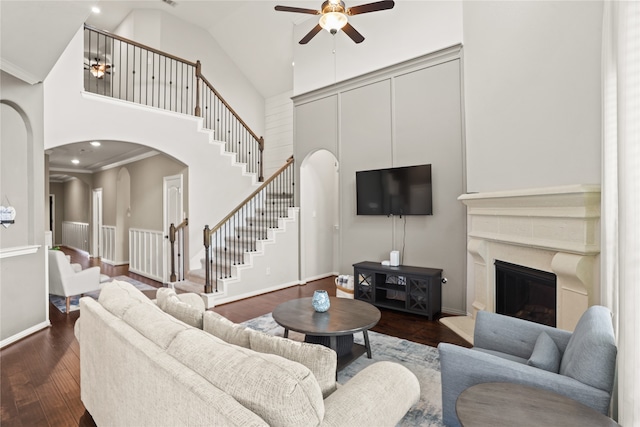 living room with crown molding, a fireplace, dark wood-type flooring, and high vaulted ceiling