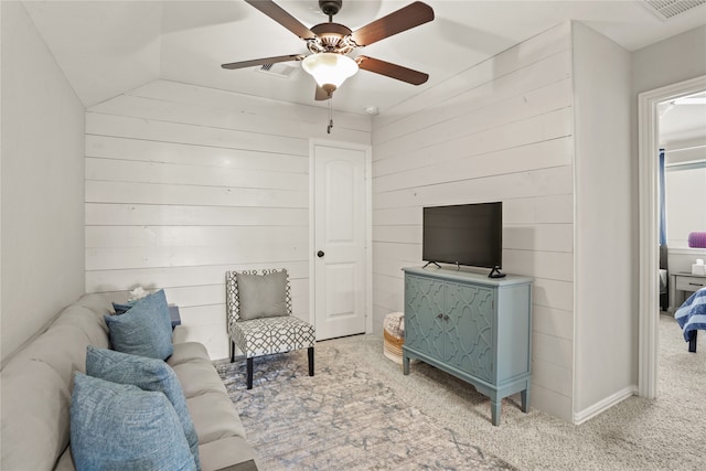 living room with wooden walls, lofted ceiling, ceiling fan, and carpet floors