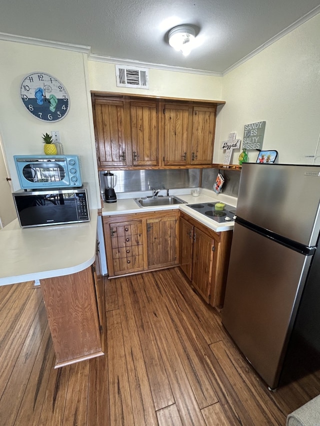 6102 Seawall Blvd Unit 375, Galveston, TX 77551 - kitchen featuring freestanding refrigerator, brown cabinetry, a sink, crown molding, and light countertops
