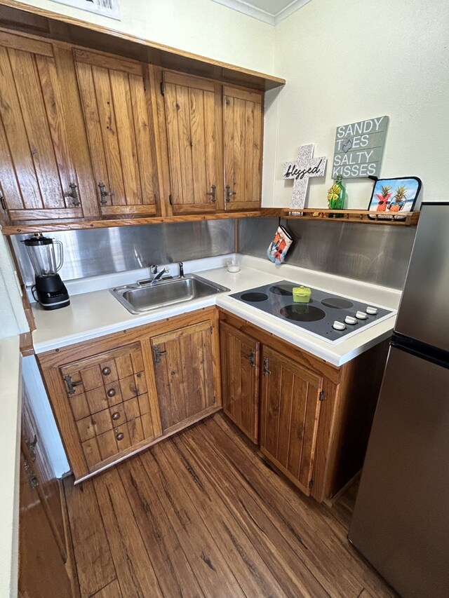 6102 Seawall Blvd Unit 375, Galveston, TX 77551 - kitchen featuring freestanding refrigerator, dark wood-style flooring, brown cabinets, a sink, and black electric stovetop