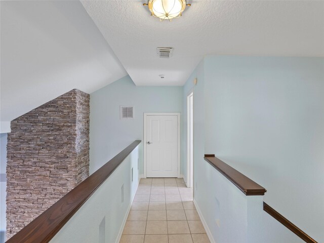 hall featuring an upstairs landing, light tile patterned flooring, and visible vents