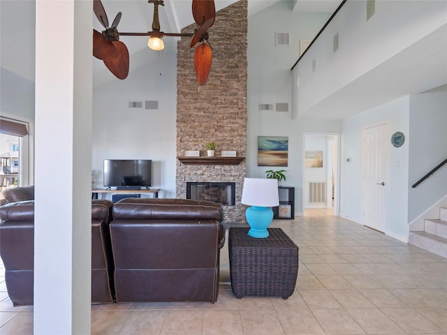 living room with tile patterned flooring, stairway, a stone fireplace, baseboards, and high vaulted ceiling