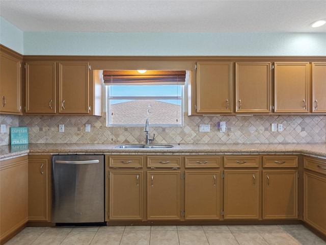 kitchen with light tile patterned floors, stainless steel dishwasher, a sink, light countertops, and backsplash