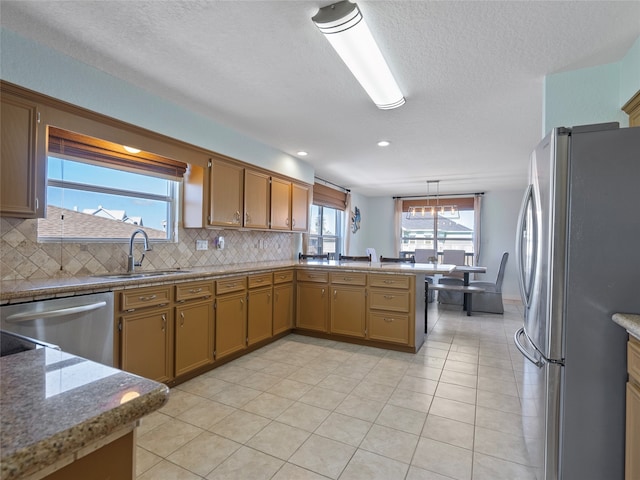 kitchen with light tile patterned flooring, kitchen peninsula, stainless steel appliances, and tasteful backsplash