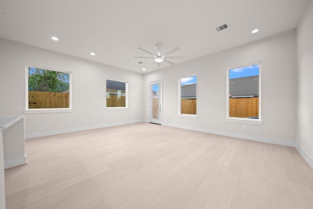 empty room with ceiling fan, a healthy amount of sunlight, and light hardwood / wood-style floors