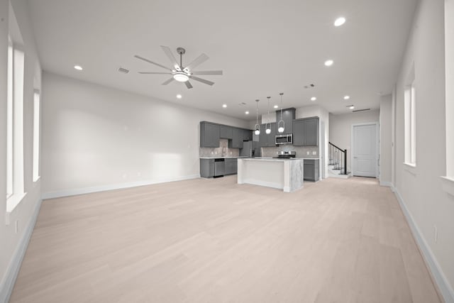 unfurnished living room featuring ceiling fan and light hardwood / wood-style flooring