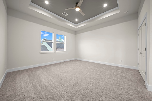 carpeted empty room featuring crown molding, a tray ceiling, and ceiling fan