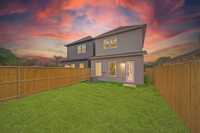 back house at dusk with central AC and a yard