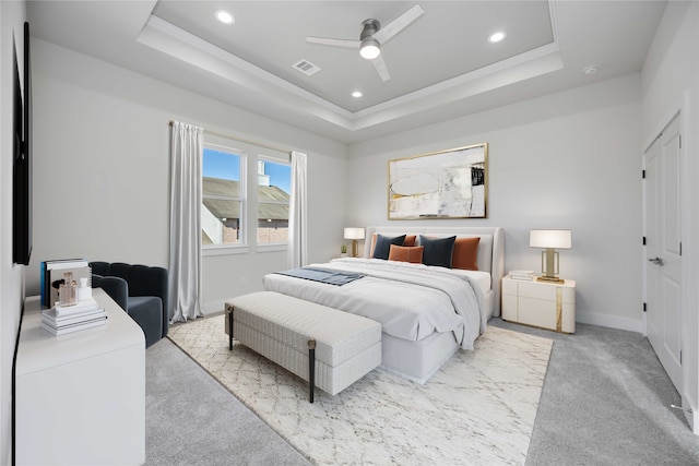 bedroom featuring light carpet, a tray ceiling, and ceiling fan