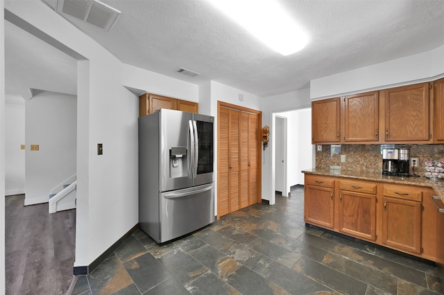 kitchen with dark stone counters, decorative backsplash, a textured ceiling, and stainless steel fridge with ice dispenser