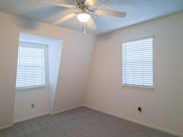 spare room featuring a healthy amount of sunlight, dark colored carpet, and ceiling fan