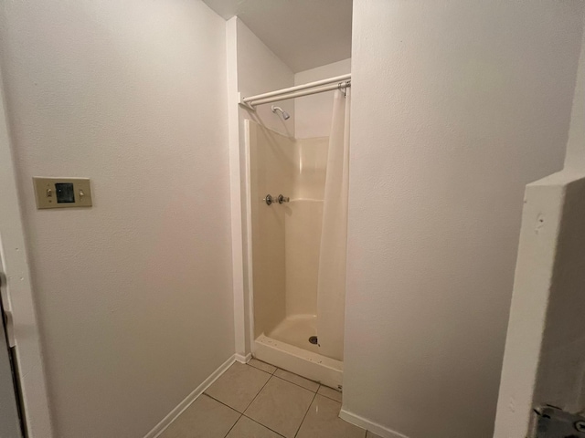 full bathroom featuring tile patterned floors, baseboards, and a stall shower