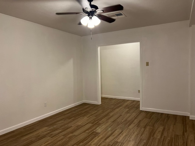 spare room with baseboards, visible vents, dark wood-style floors, and ceiling fan
