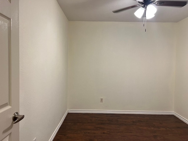 empty room featuring dark wood finished floors, a ceiling fan, and baseboards
