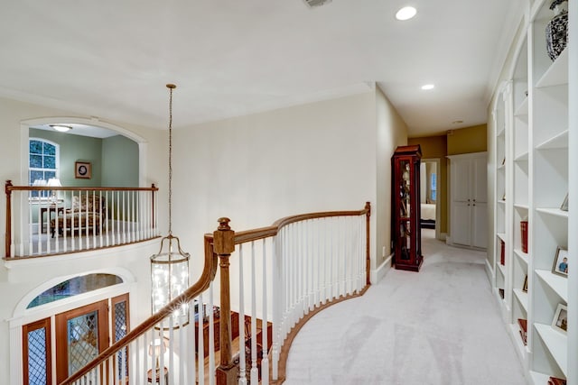 hall with built in features, light colored carpet, and ornamental molding