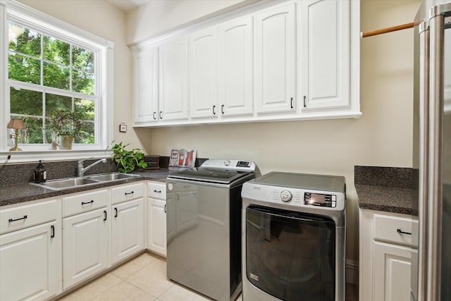 washroom with cabinets, light tile patterned floors, washer and dryer, and sink