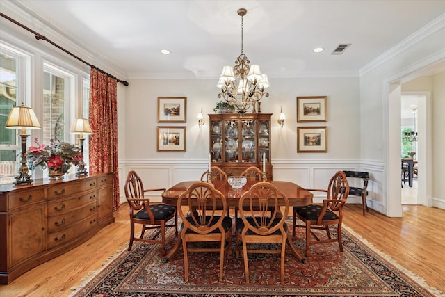 dining area featuring light hardwood / wood-style flooring, a healthy amount of sunlight, a notable chandelier, and ornamental molding