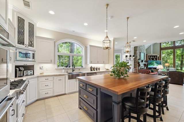 kitchen featuring a kitchen island, stainless steel microwave, white cabinetry, and wooden counters