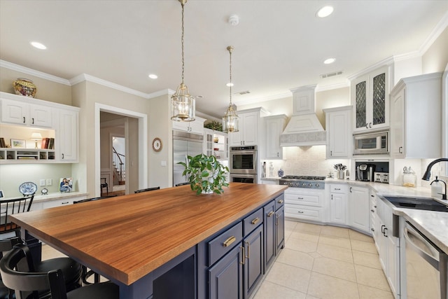 kitchen with built in appliances, a center island, white cabinets, and blue cabinetry