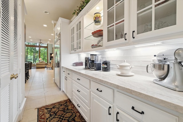 bar featuring decorative backsplash, light tile patterned floors, white cabinets, and built in fridge