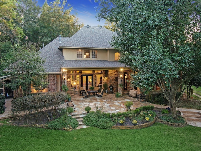 back house at dusk with a lawn, ceiling fan, and a patio