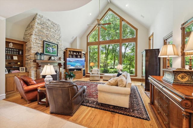 living room featuring a fireplace, light wood-type flooring, high vaulted ceiling, and ceiling fan