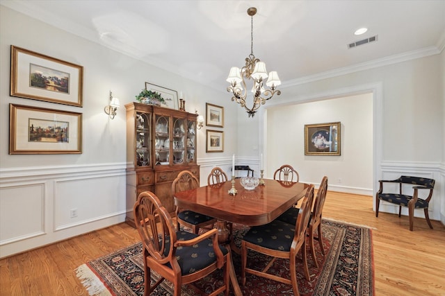 dining area featuring a notable chandelier, light hardwood / wood-style floors, and crown molding