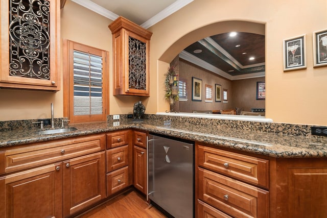 kitchen featuring dark stone countertops, ornamental molding, light hardwood / wood-style flooring, and sink