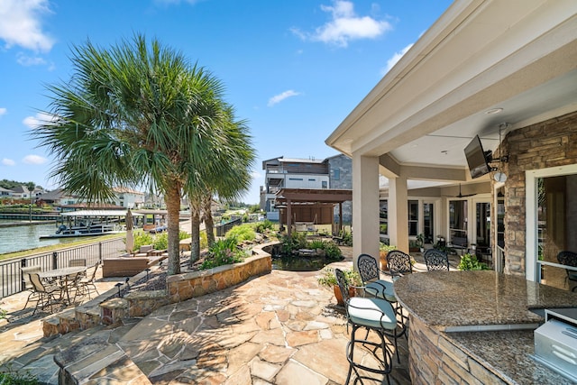 view of patio featuring an outdoor bar, a water view, and ceiling fan